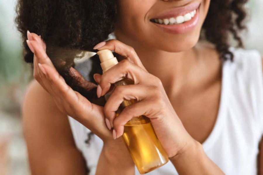 Una donna che spruzza i suoi capelli naturalmente ricci con olio per la cura dei capelli