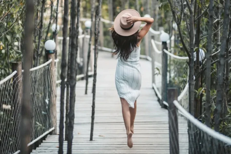 A woman wearing a wide-brim fedora in sunny weather