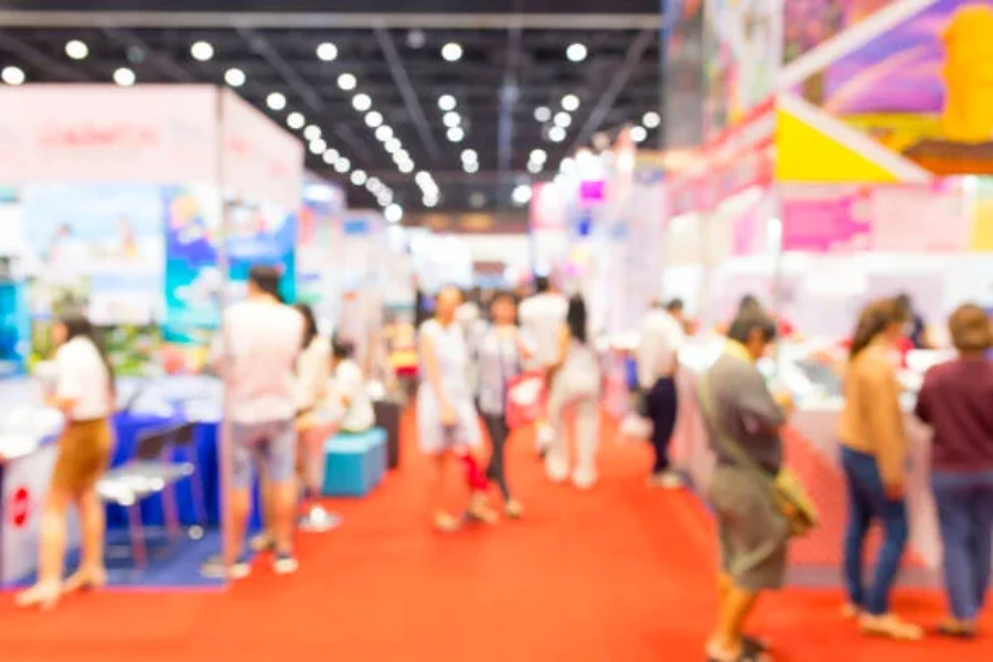 An exhibition with people walking around and an orange rug