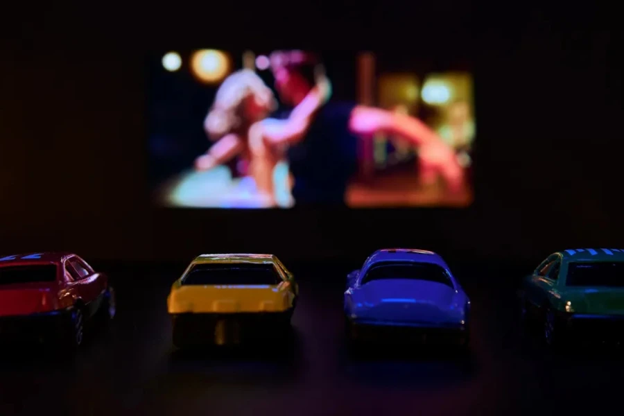 Blurred photo of toy cars parked in front of large movie screen