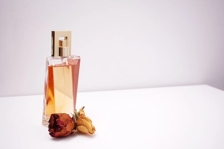 Clear glass perfume bottle next to a flower