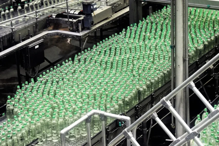 Glass bottles on top of a plastic packaging machine