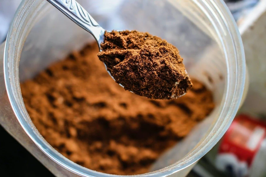 Image of a spoon with scooped protein powder from a jar