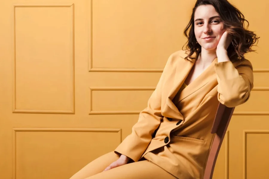 Lady in a neutral pant suit sitting on a chair