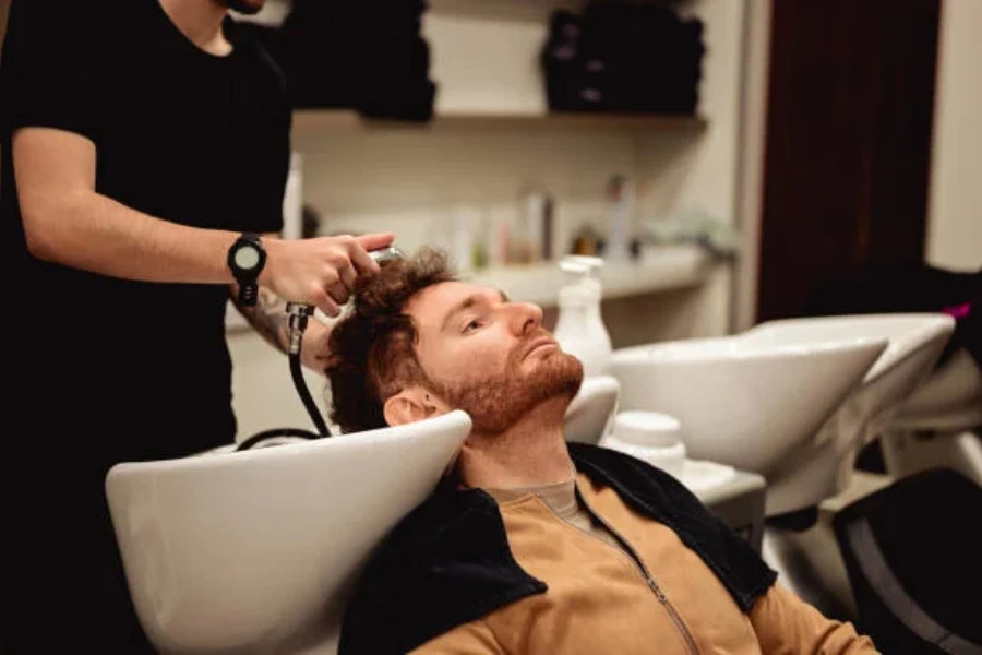 Man with head in sink having hair washed
