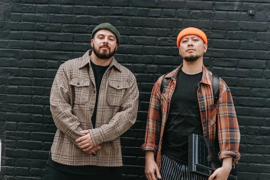 Men posing near a brick wall while wearing shackets