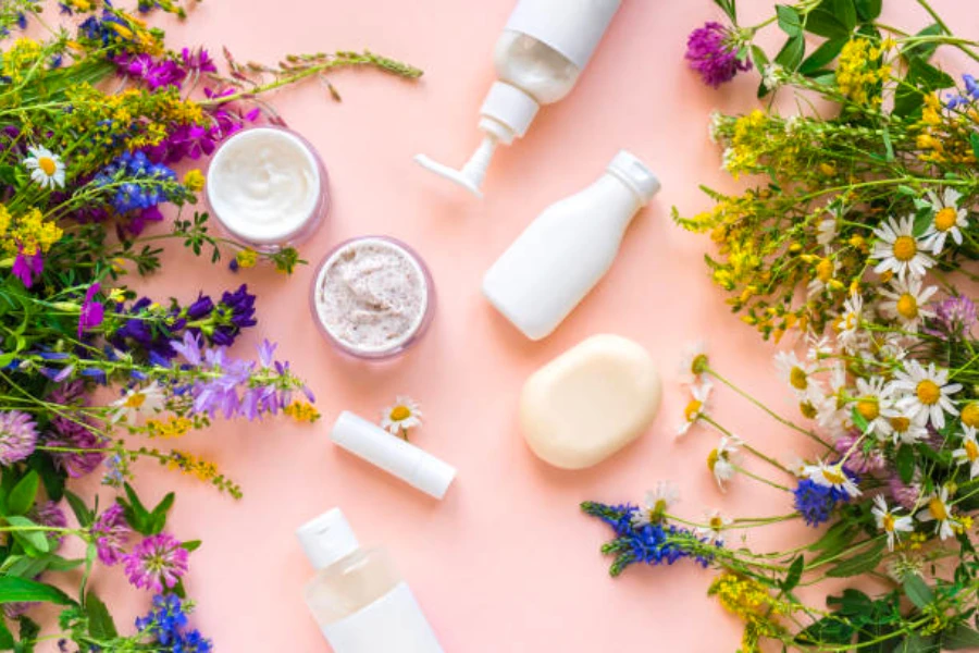 Natural beauty products on a pink background with plants and flowers