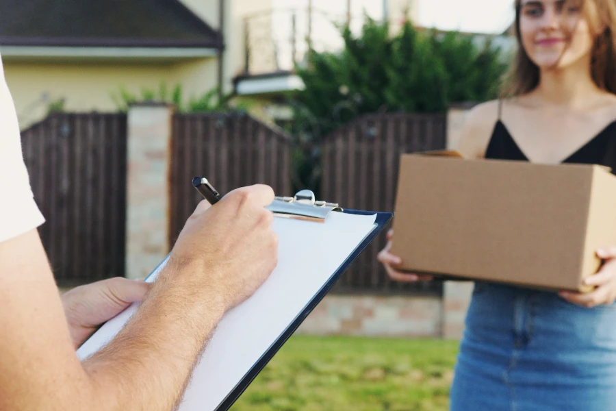 person delivering a box while another person signs for package