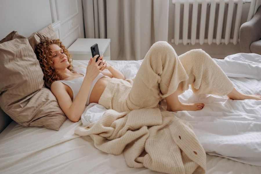 woman laying on top of bedsheets