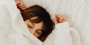 woman sleeping with face half under sheet