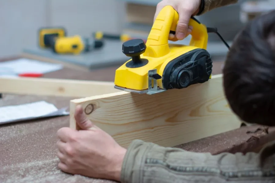 workman operating powerful handheld electric wood planer