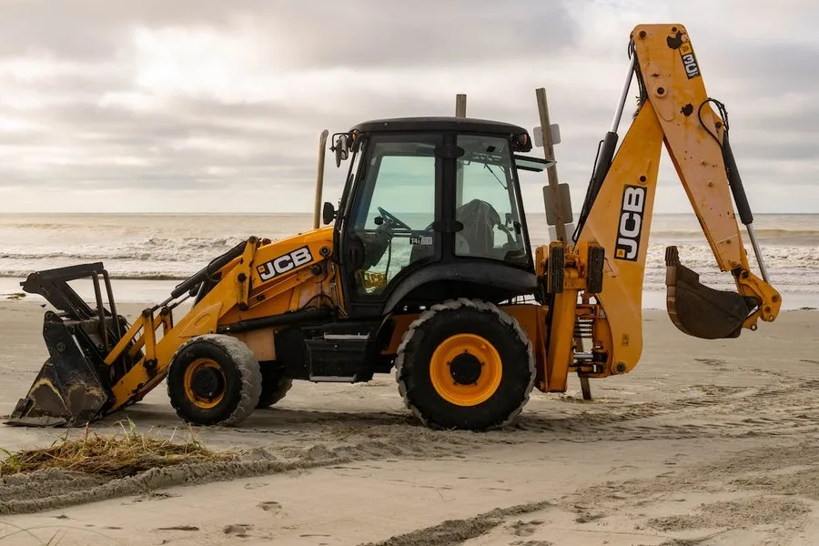 A backhoe tractor on a beach