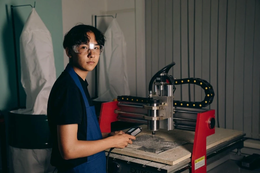 A man in blue apron using a CNC machine