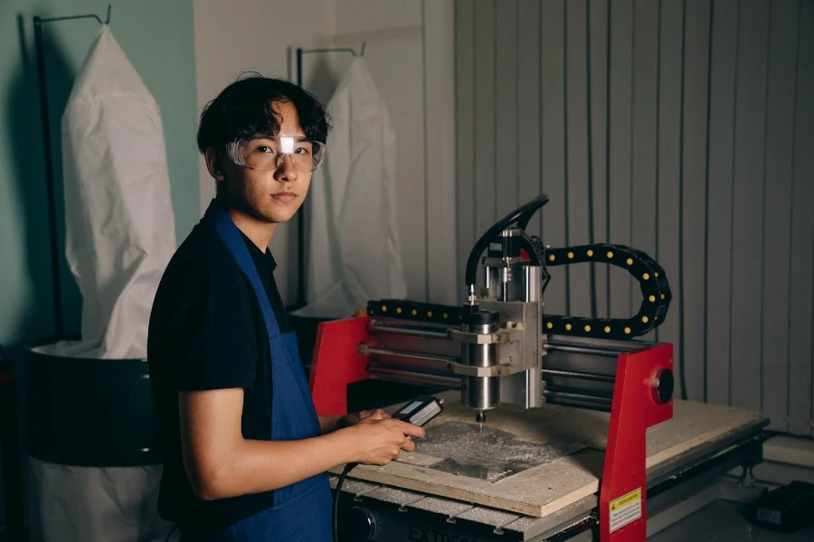 Ein Mann in blauer Schürze bedient eine CNC-Maschine