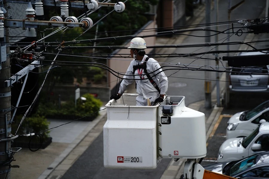 A person working on overhead cables