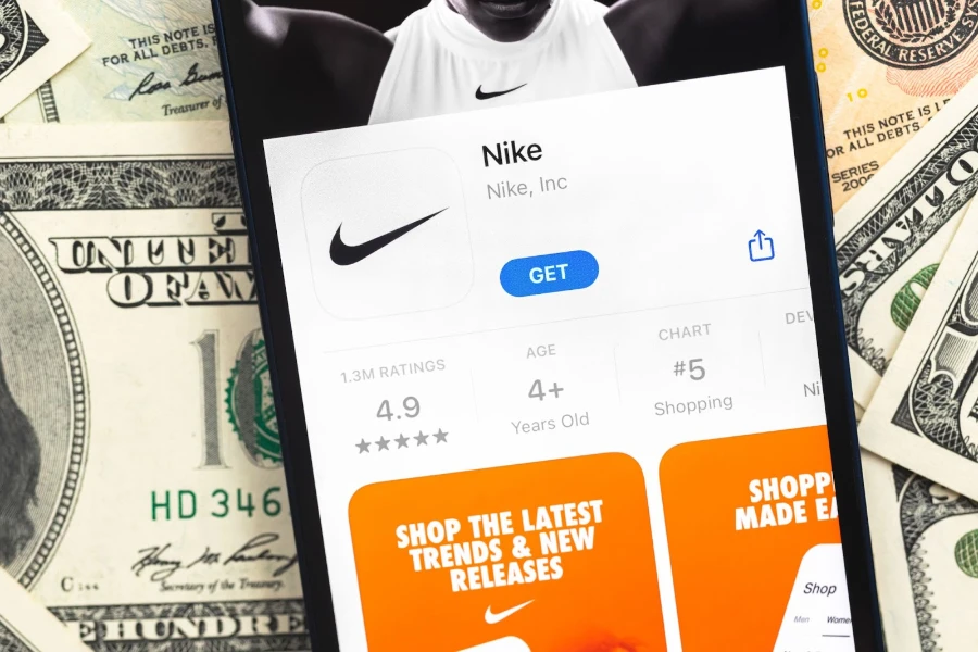 A phone on top of dollar bills is open to the App Store’s Nike page