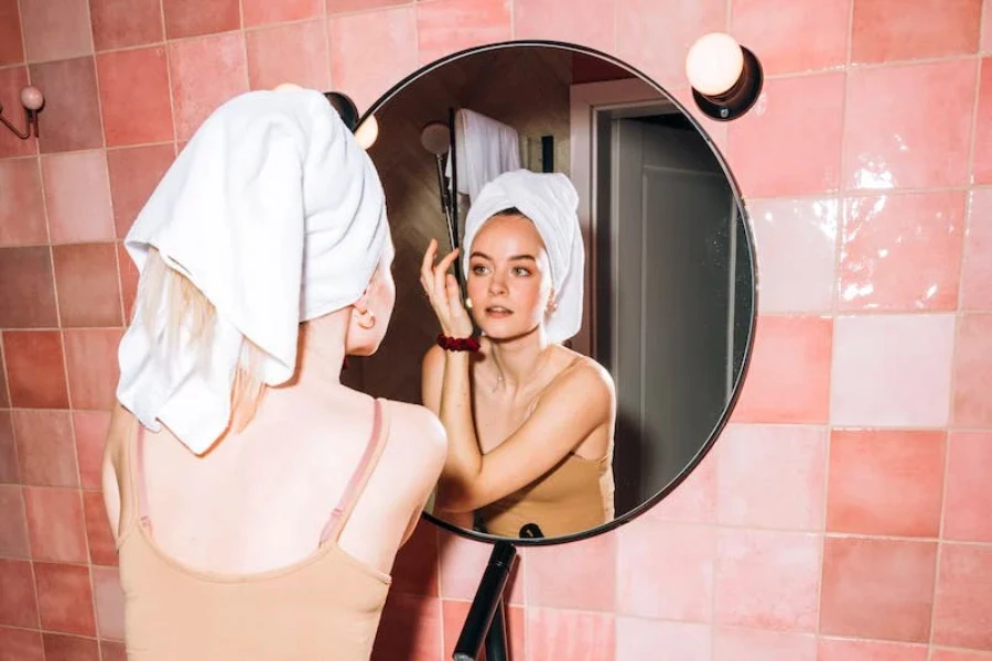 A woman looking in the mirror applying skin cream