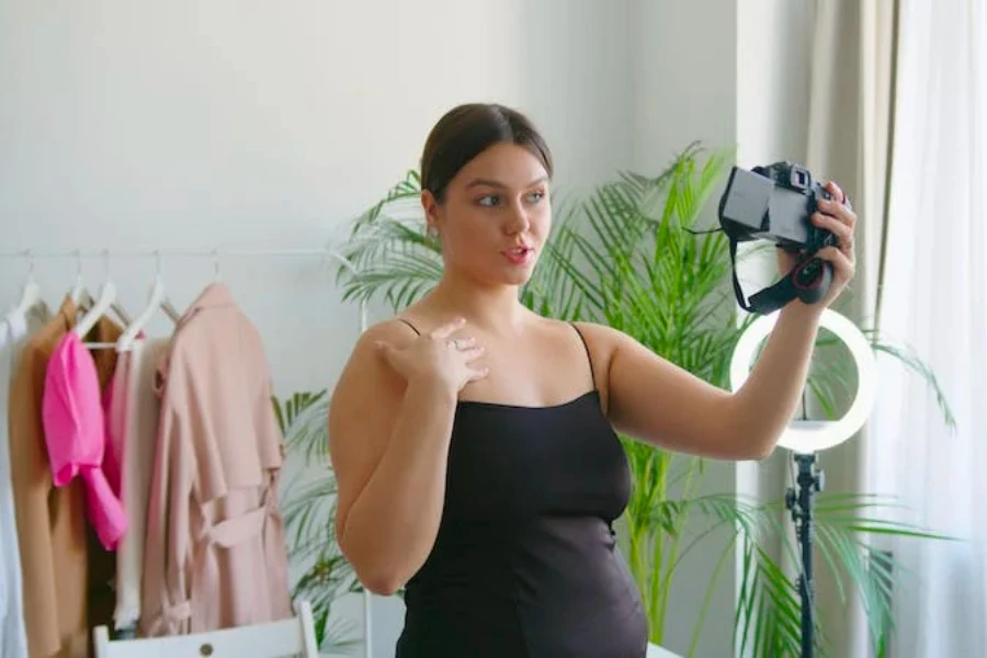 A woman recording herself with clothes in the background
