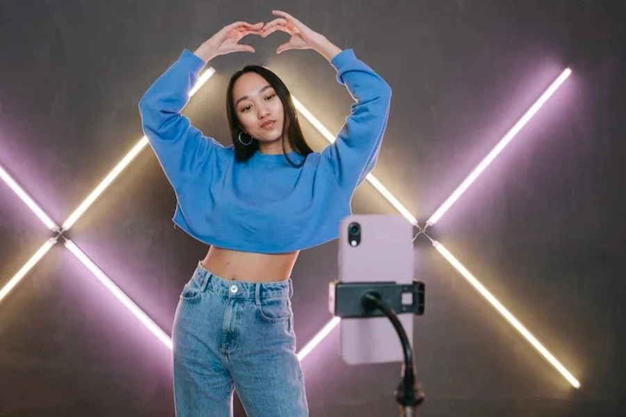 A woman recording herself with neon lights in the background