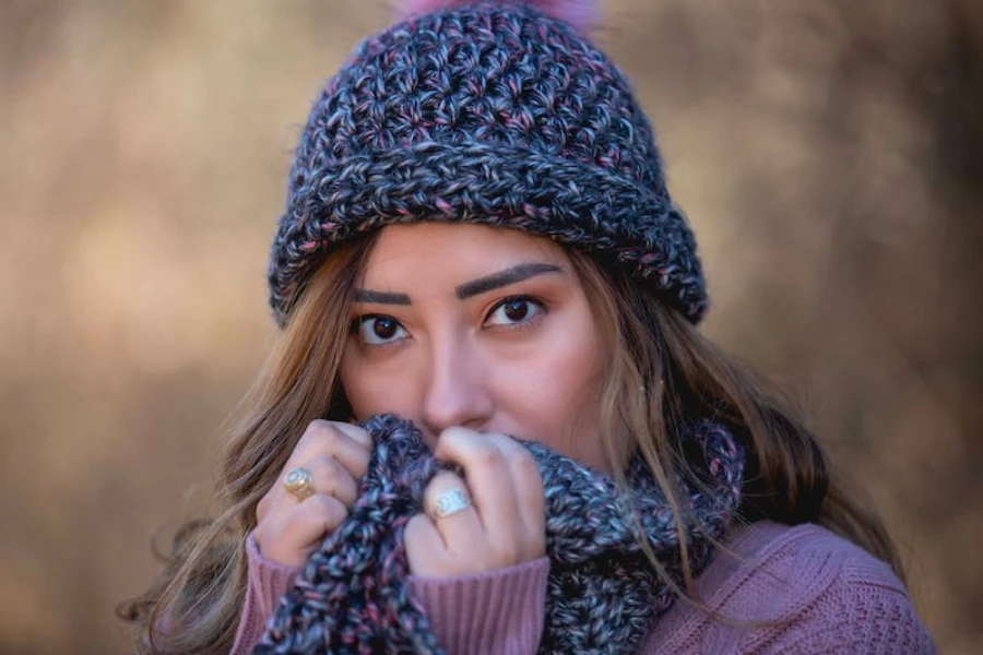 A woman wearing a multicolored crochet beanie with a brown background