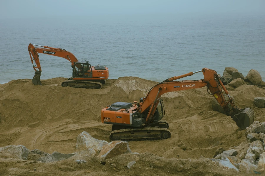 Excavadoras que operan en arena cerca del agua