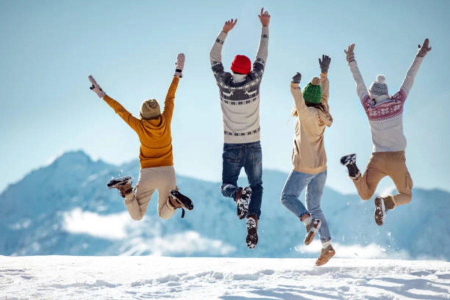 Four people in winter gear and jumping in the air