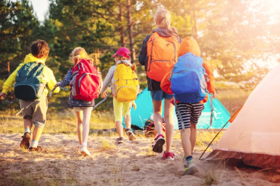 Group of children at campsite wearing variety of backpacks
