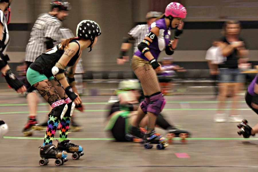 Grupo de patinadores de roller derby patinando ativamente com equipamento de segurança