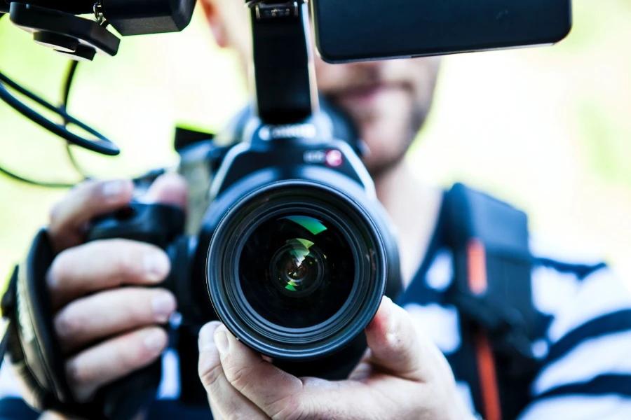 uomo che tiene la fotocamera e il microfono collegati alla fotocamera