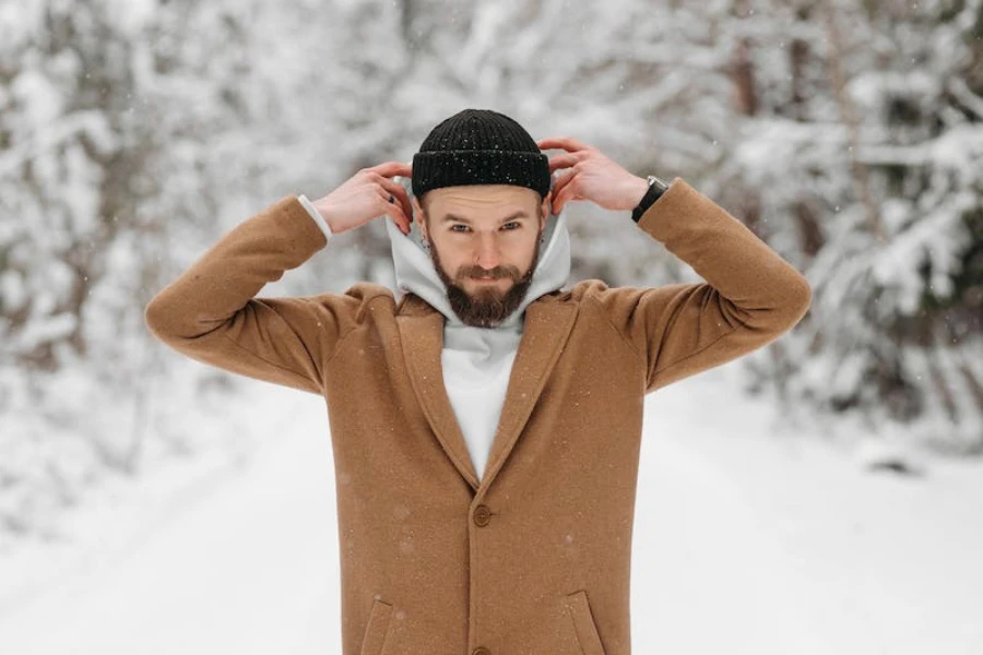 Mann steht draußen im Schnee und trägt eine Wintermütze