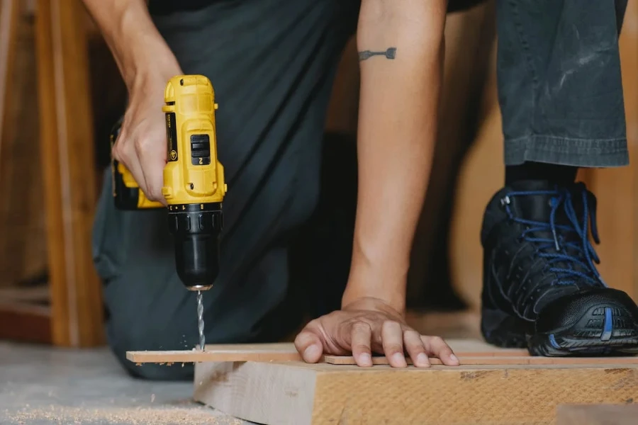 Man using a drill machine to drill a wood