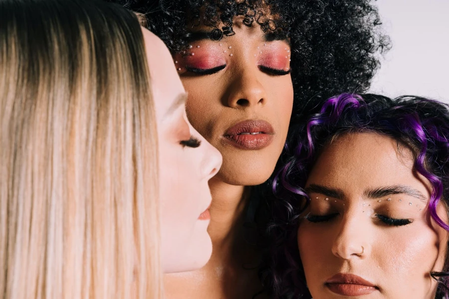 Three women of different ethnicities wearing experimental makeup