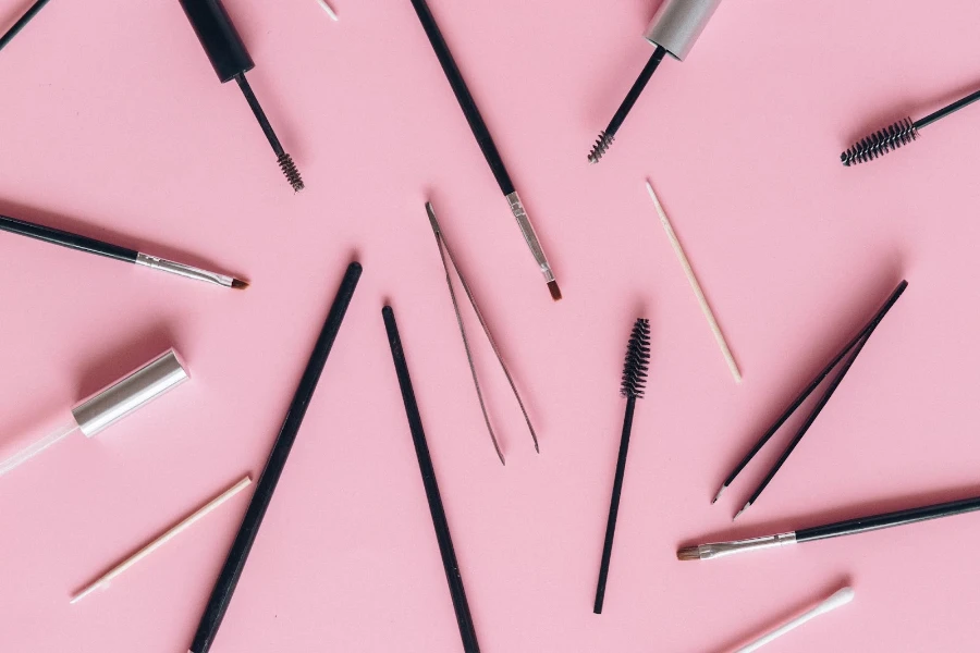 Various makeup tools on pink background