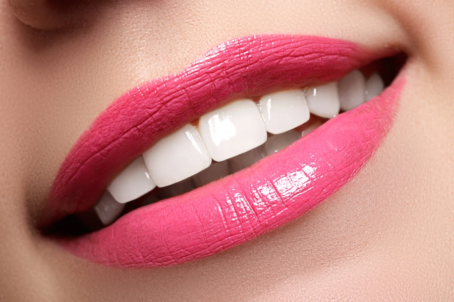 Dientes blancos con labios de color rosa brillante.