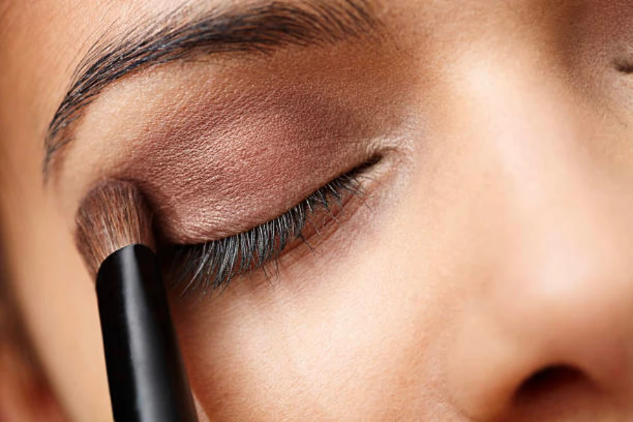 Woman applying brown eyeshadow to her eyelid