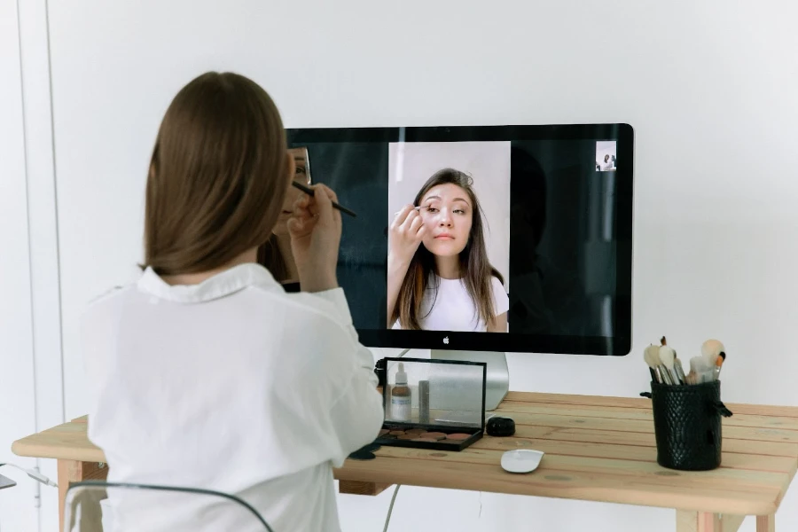 Woman applying makeup on desktop screen