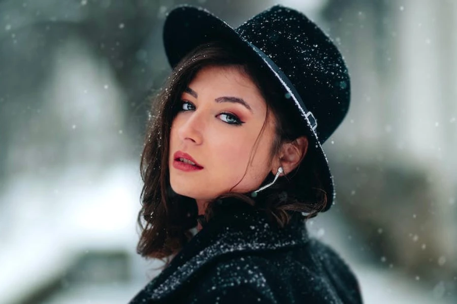Woman in the snow wearing a black boater hat