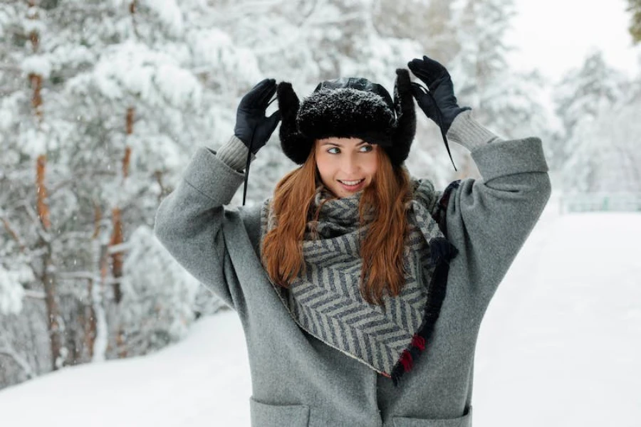 Donna nella neve che indossa un cappello da trapper nero fuzzy