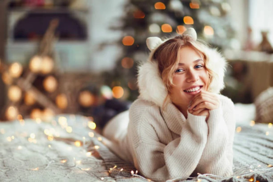 Woman laying on a bed wearing white fuzzy earmuffs