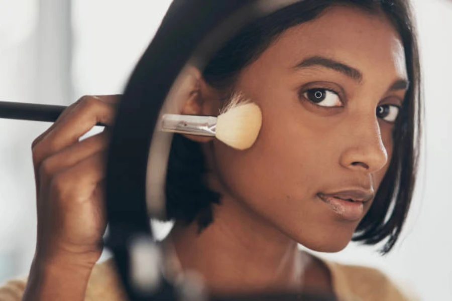 Femme à l'aide d'une brosse sculptante pour modeler son visage