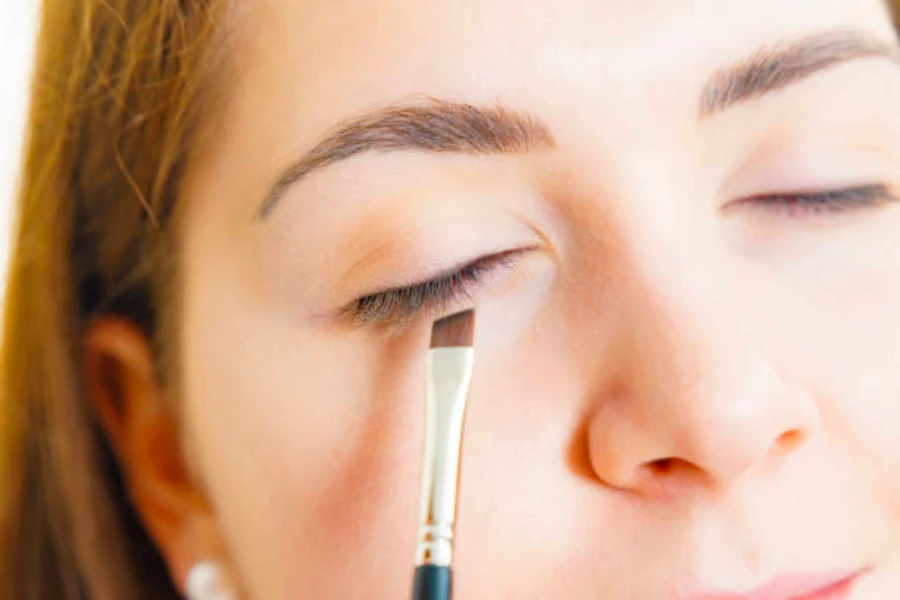 Eyeliner uygulamak için kanatlı astar fırçası kullanan kadın