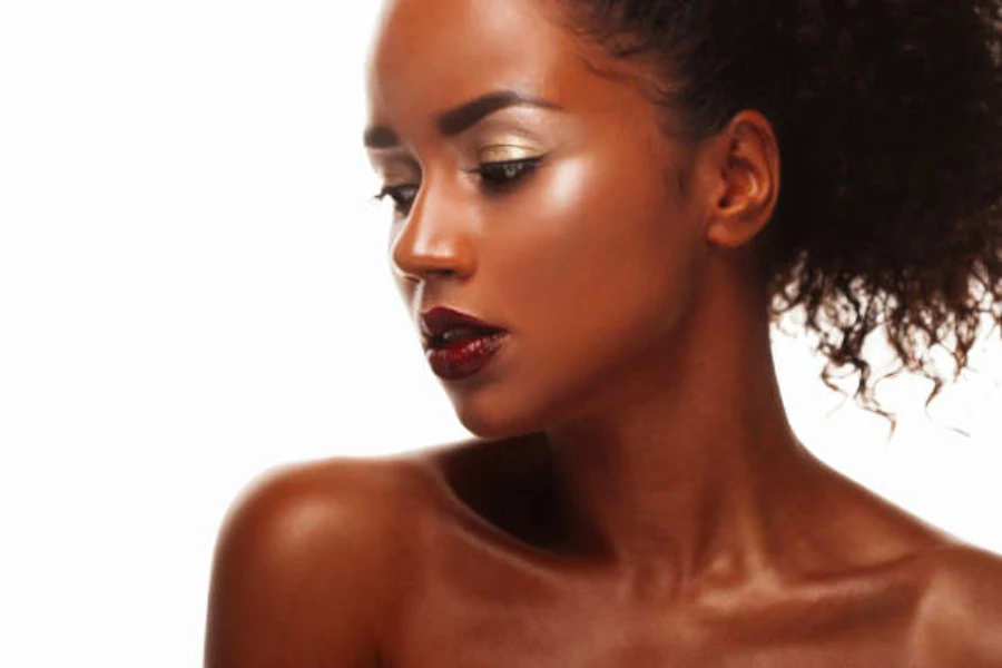 Woman with black curly hair wearing shiny gold eyeshadow