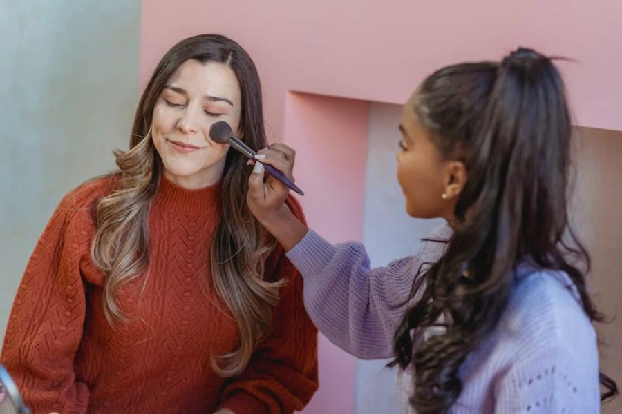 Frauen tragen Make-up mit einem Teintpinsel auf