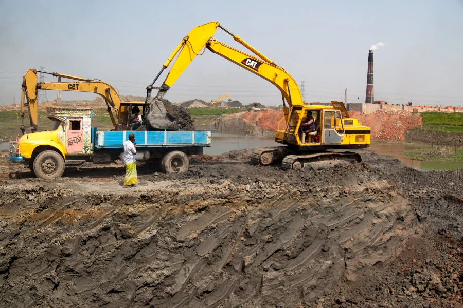 Yellow backhoe putting soil on truck