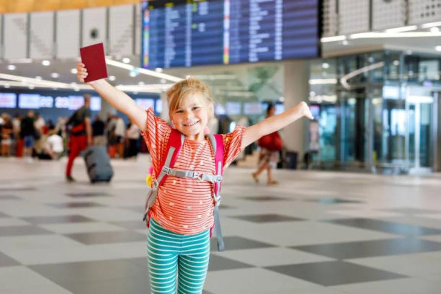 Giovane ragazza all'aeroporto che tiene il passaporto e indossa uno zaino comodo