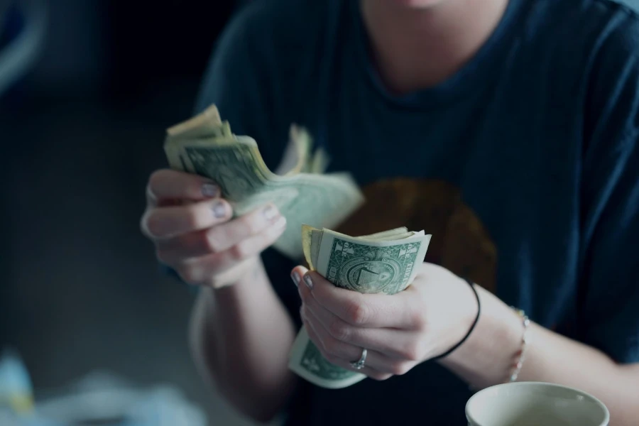 una señora contando dinero después de vender algunas computadoras portátiles viejas