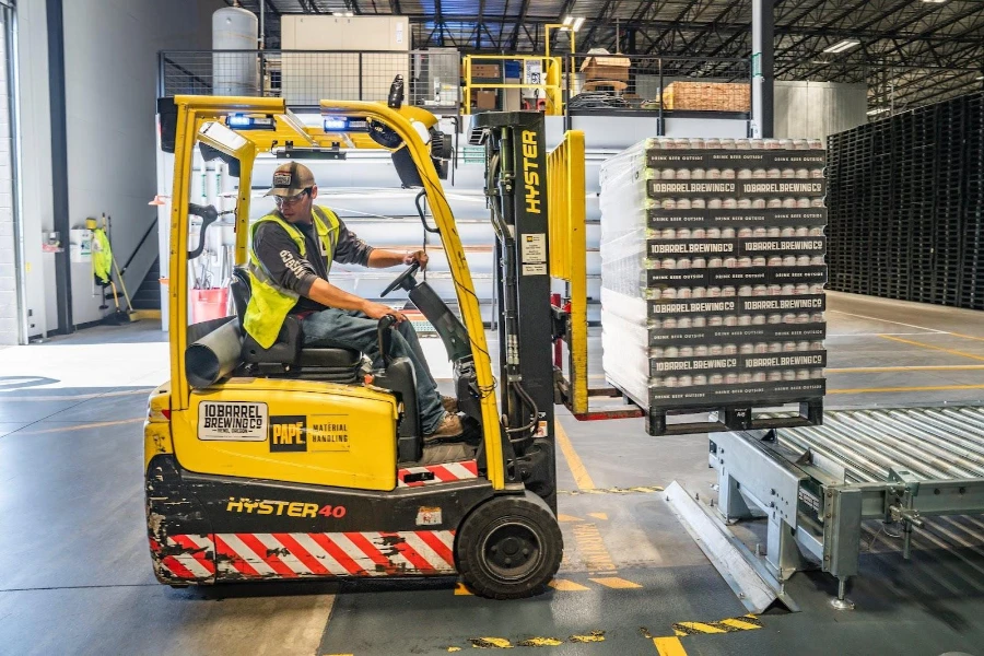 A man driving a lift truck in a warehouse full of goods