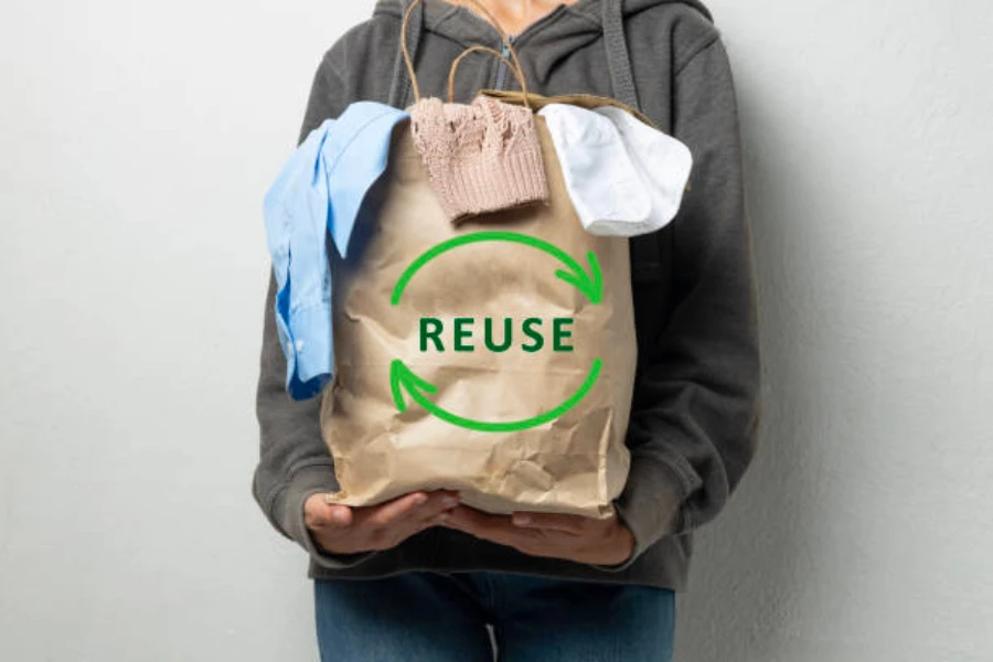 A person holding a bag of clothes labeled reuse