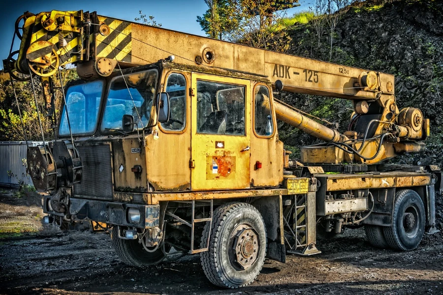 A used yellow crane truck at a construction site