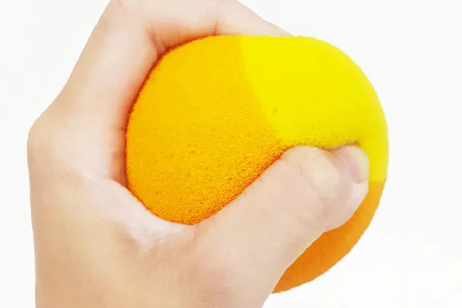 Hand squeezed a yellow and orange foam tennis ball